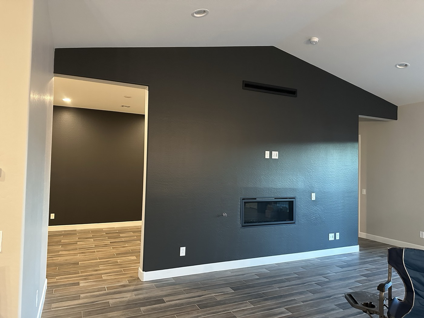 Vaulted living room with a full-height charcoal accent wall wrapping a linear fireplace