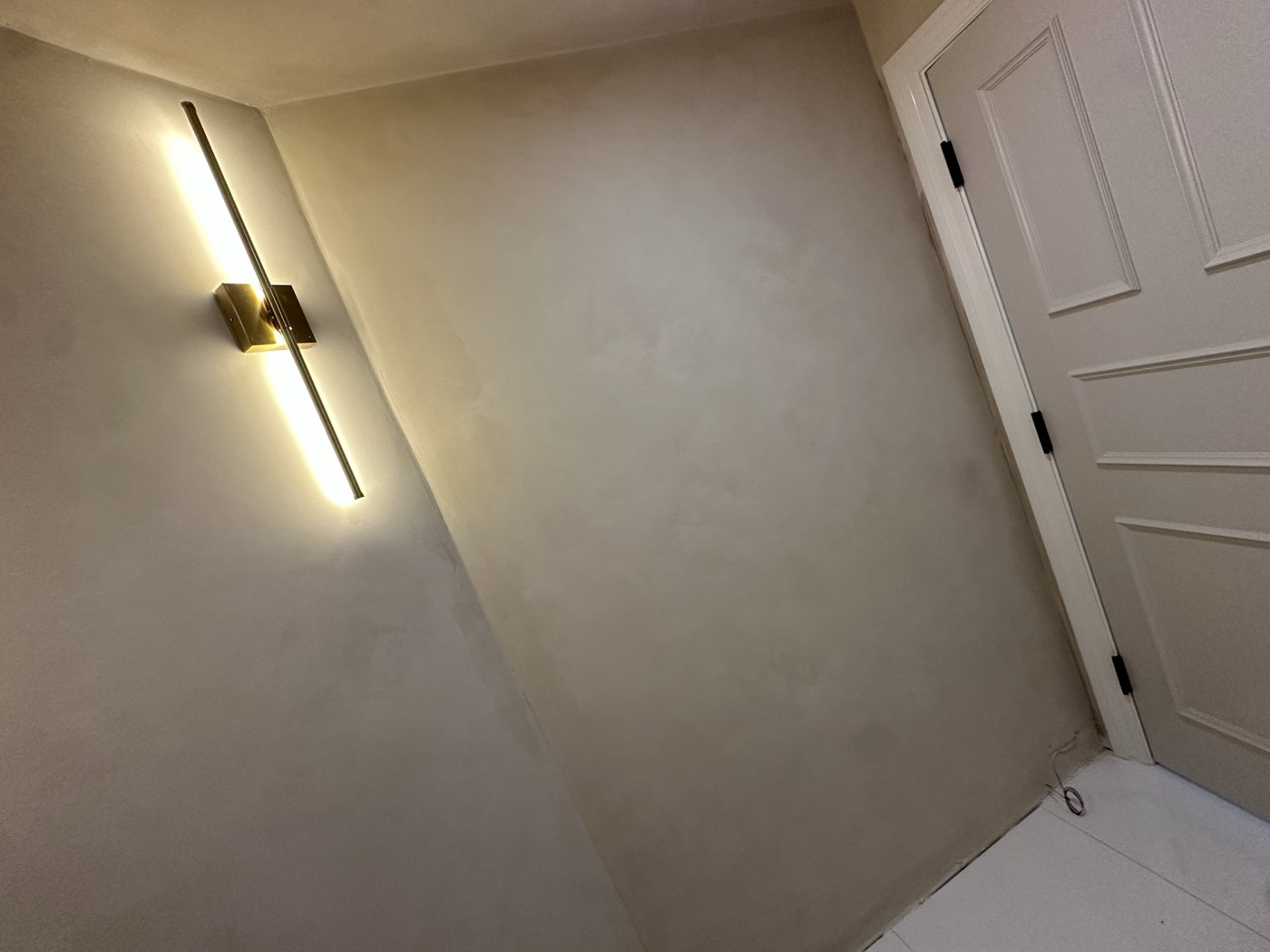 Cream limewash wall raked by a linear brass sconce, Phoenix