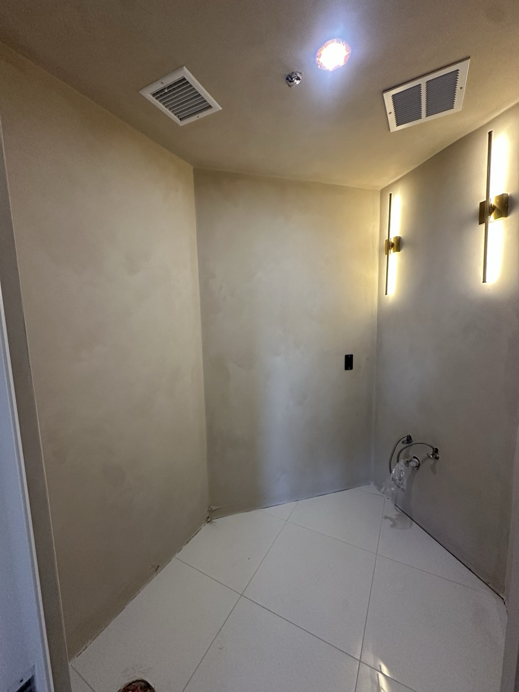 Cream limewash laundry room walls lit by two brass sconces, Phoenix