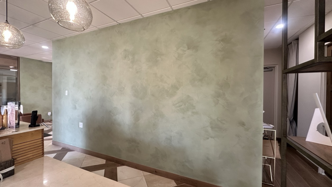 Sage-green limewash feature wall in a Phoenix salon lobby