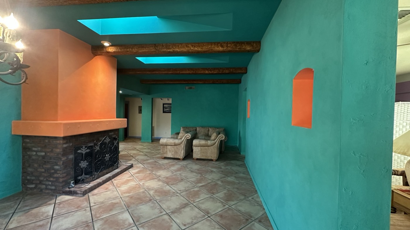 Teal limewash great room walls with exposed vigas and a terracotta fireplace