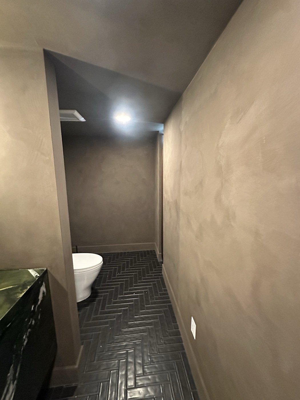 Taupe microcement powder room walls over black herringbone tile, Phoenix