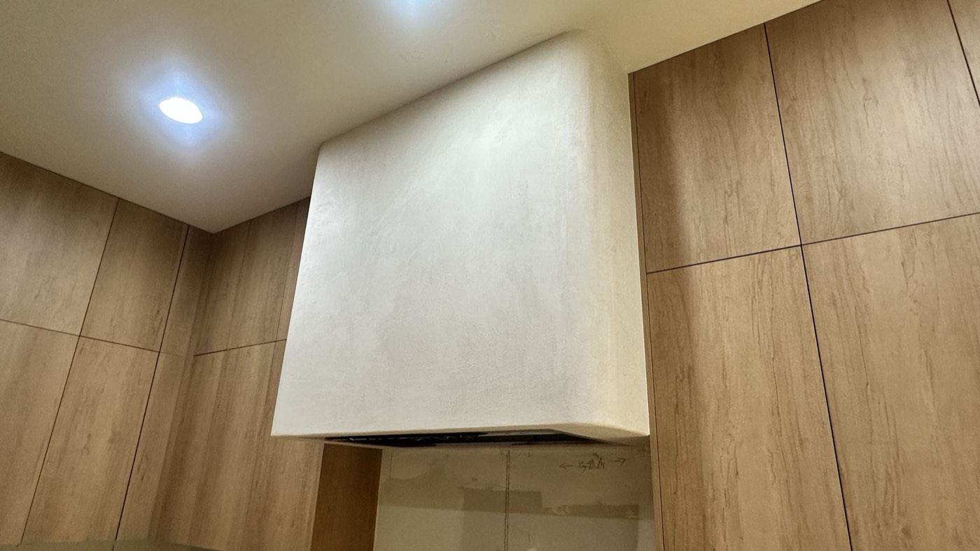 Hand-troweled microcement range hood between oak slab cabinets in a Phoenix kitchen