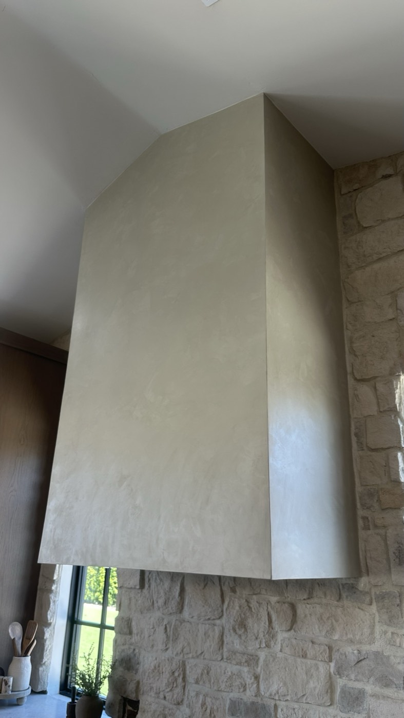 Moroccan clay plastered range hood against a stacked stone wall, Phoenix kitchen