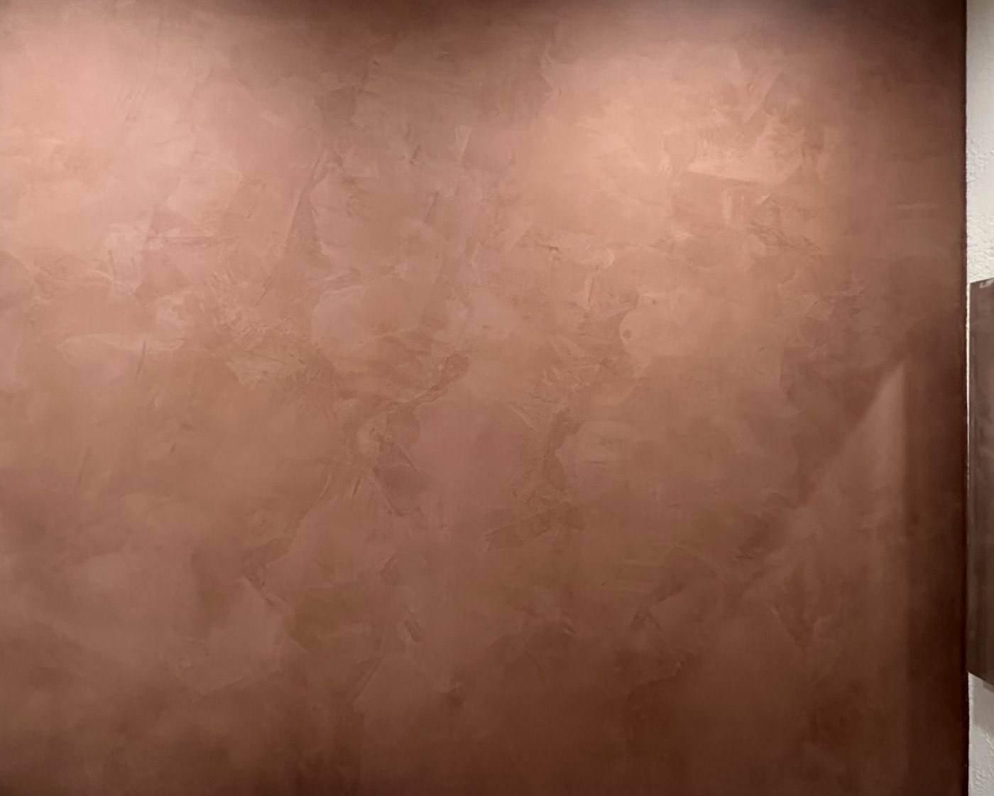 Close detail of copper-toned clay plaster showing hand-troweled cloud movement