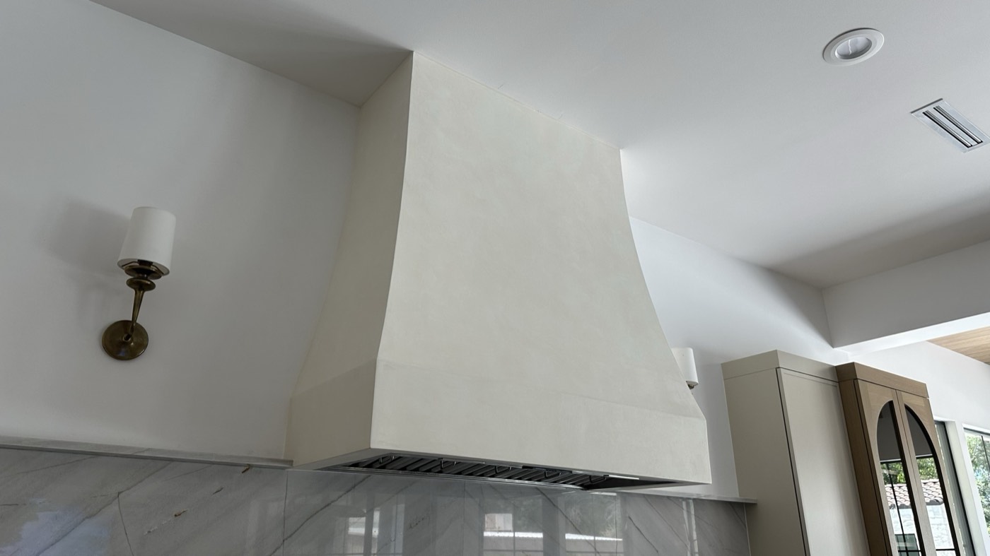 Curved Roman clay range hood over a marble slab backsplash, Phoenix kitchen